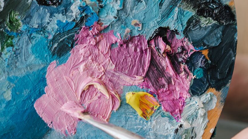 close up shot of a person holding a palette and a paintbrush